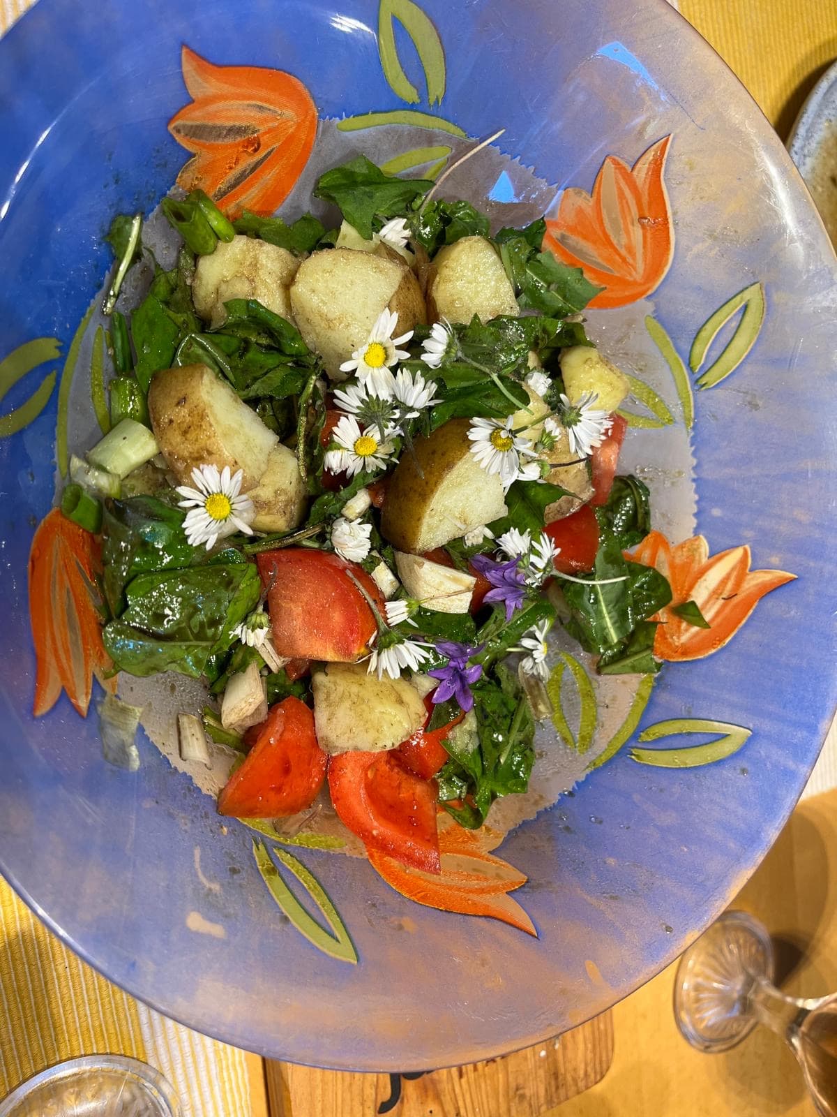 Kartoffelsalat mit Tomaten, Spinat und essbaren Blüten in einer blau bemalten Schale